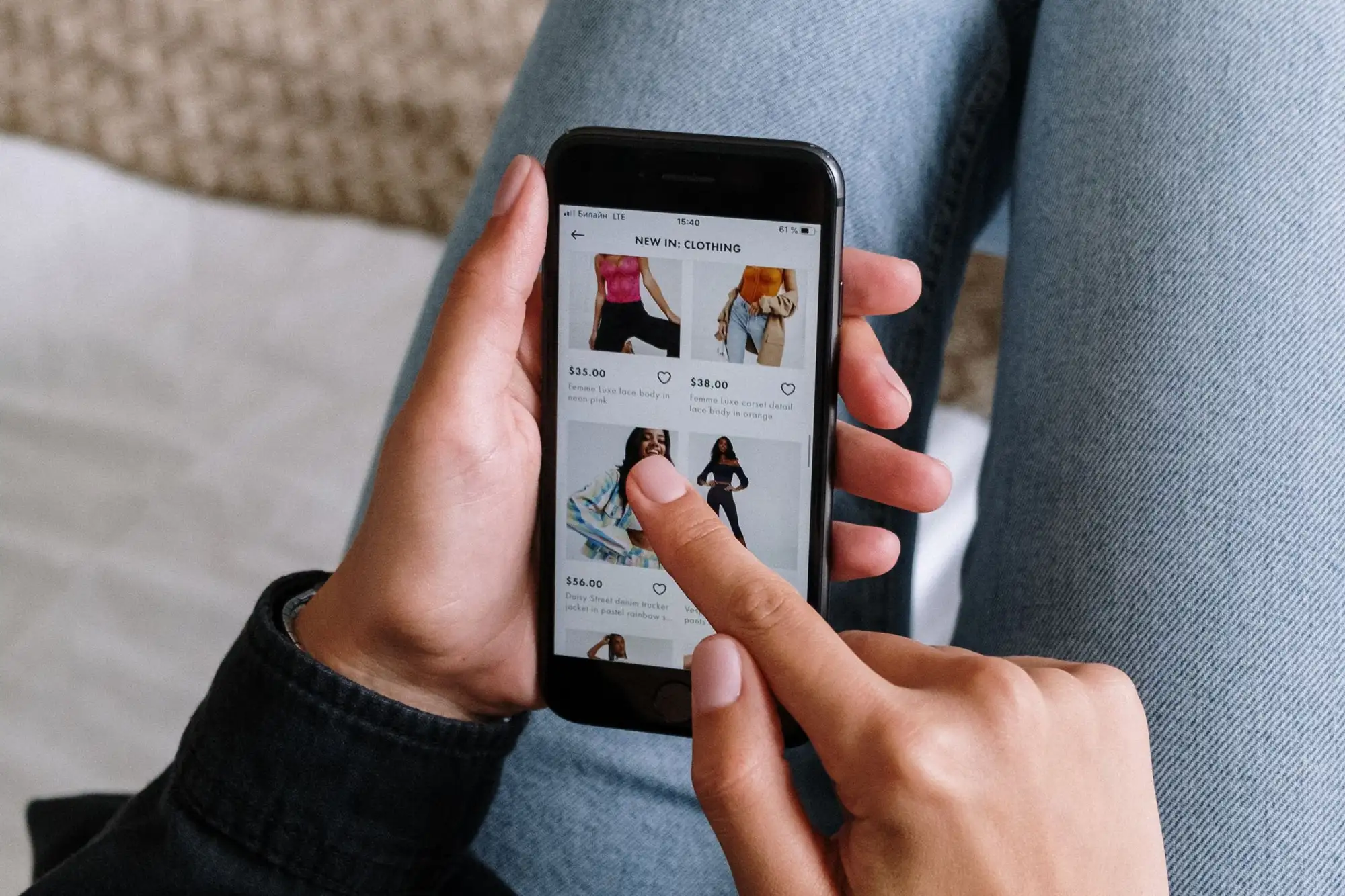 Hands holding a phone showing an online clothing store