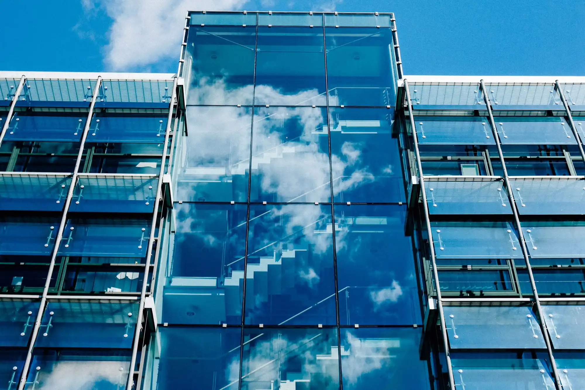Glass facade of a modern office building reflecting the sky